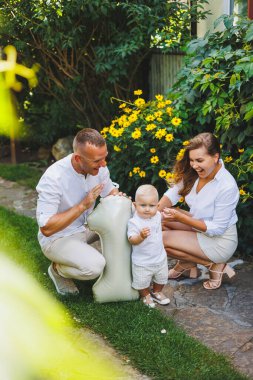 Sevgi dolu anne ve babalar, oğullarının doğadaki ilk yılını kutluyorlar. Mutlu aile küçük oğullarına sarılıyor..