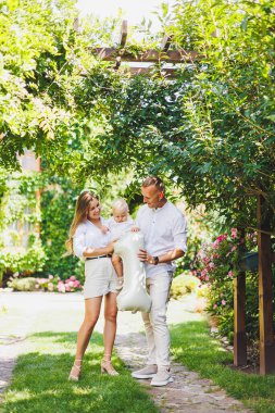 Sevgi dolu anne ve babalar, oğullarının doğadaki ilk yılını kutluyorlar. Mutlu aile küçük oğullarına sarılıyor..