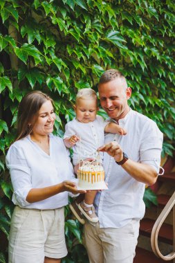 Anne ve baba doğada bir yaşındaki oğullarıyla birlikte ilk doğum gününü pastayla kutluyorlar. Doğumgünü Doğada bir pasta.