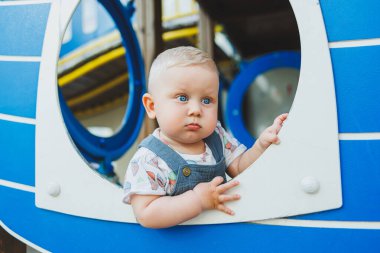 Çocuk parkında gülümseyen 1 yaşında bir çocuk oynuyor. Çocukların açık hava oyun alanı.