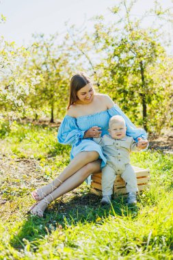 Genç ve mutlu bir anne doğada dururken küçük oğlunu kollarına alır. Bir çocukla yürüyüş. Anne bir bebekle yürüyüşe çıktı..