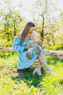 Genç ve mutlu bir anne doğada dururken küçük oğlunu kollarına alır. Bir çocukla yürüyüş. Anne bir bebekle yürüyüşe çıktı..