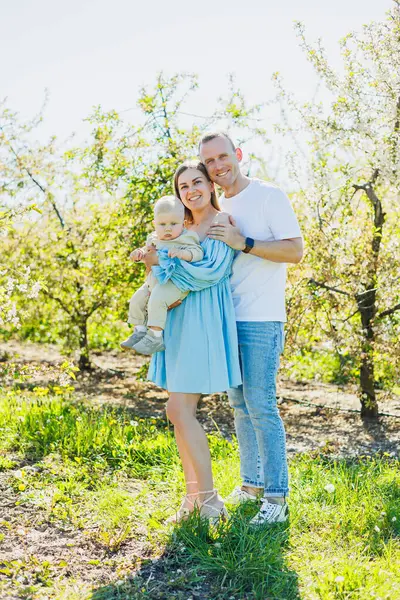 Çiçek açan bir bahçede küçük bir oğlu olan genç bir çift. Bahçede çocuklu mutlu bir aile çifti..