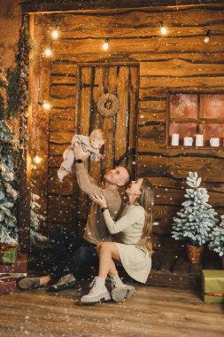 Genç anne ve baba evdeki Noel ağacının yanında otururken çocuklarıyla oynuyorlar. Noel aile ortamı