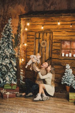 Genç anne ve baba evdeki Noel ağacının yanında otururken çocuklarıyla oynuyorlar. Noel aile ortamı