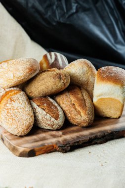 Ev yapımı ekmek, buğdaylı ekmek ve hecelenmiş un. Tahta bir tahtanın üzerinde dilimlenmiş ve ikiye kesilmiş ekmek dokusu. Çıtır sandviç ekmeği