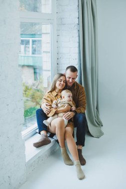 Anne ve baba beyaz arka planda bebekleriyle oynuyorlar. Sevgi dolu ailesinin kollarında bir bebek..