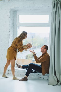 Anne ve baba beyaz arka planda bebekleriyle oynuyorlar. Sevgi dolu ailesinin kollarında bir bebek..