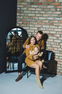 Anne ve baba beyaz arka planda bebekleriyle oynuyorlar. Sevgi dolu ailesinin kollarında bir bebek..