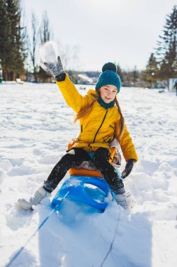 Neşeli bir kız kışın karda kızağa biner. Çocuk bir kızakla dışarı çıkıyor. Çocuklar için kış eğlencesi.