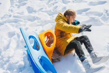 Neşeli bir kız kışın karda kızağa biner. Çocuk bir kızakla dışarı çıkıyor. Çocuklar için kış eğlencesi.