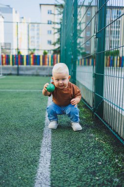 Sokakta kot pantolon ve tişört giyen küçük bir çocuk oynuyor. Erkekler için Denim giysileri. Spor sahasında bir çocuk. Çocuk gelişimi.