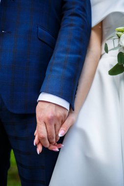 Yeni evlilerin ellerinin yakın çekimi. Bir erkek bir kadının elini tutar..