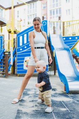Sevgi dolu bir anne sokakta oğluyla oynuyor. Mutlu anne ve gülümseyen oğul. Çocukla aile ilişkileri.