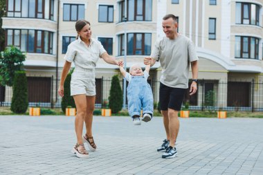 Mutlu bir evli çift yaz günü oğullarıyla dışarıda oynuyorlar. Mutlu aile kavramı. Baba, anne ve oğlu bahçede oynuyorlar..