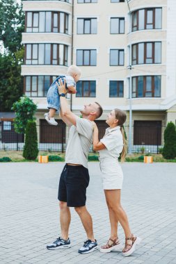 Mutlu bir evli çift yaz günü oğullarıyla dışarıda oynuyorlar. Mutlu aile kavramı. Baba, anne ve oğlu bahçede oynuyorlar..