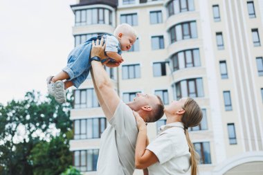 Mutlu bir evli çift yaz günü oğullarıyla dışarıda oynuyorlar. Mutlu aile kavramı. Baba, anne ve oğlu bahçede oynuyorlar..