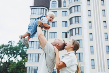 Mutlu bir evli çift yaz günü oğullarıyla dışarıda oynuyorlar. Mutlu aile kavramı. Baba, anne ve oğlu bahçede oynuyorlar..