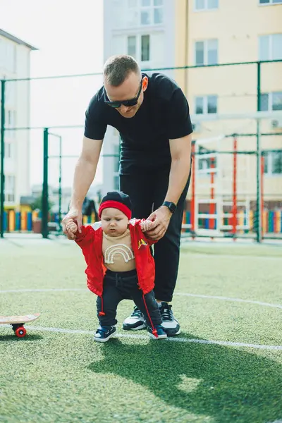 Mutlu baba küçük oğluna ilk adımlarını atmasını öğretiyor. Baba ve çocuk sokakta oynuyorlar..