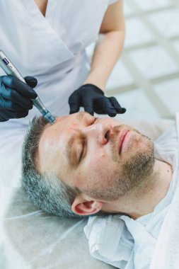 Güzellik salonunda erkek kozmetolojisi. Bir erkek yüz derisine dikkat eder..