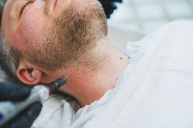 Bir kozmetikçi bir adamın derisini temizler. Kozmetik kliniğinde yüz ameliyatı yapan bir adam. Erkek kozmetolojisi.