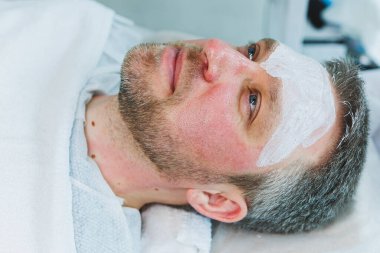 Bir kozmetikçi bir adamın derisini temizler. Kozmetik kliniğinde yüz ameliyatı yapan bir adam. Erkek kozmetolojisi.