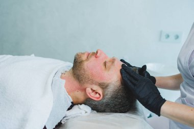 Bir kozmetikçi bir adamın derisini temizler. Kozmetik kliniğinde yüz ameliyatı yapan bir adam. Erkek kozmetolojisi.
