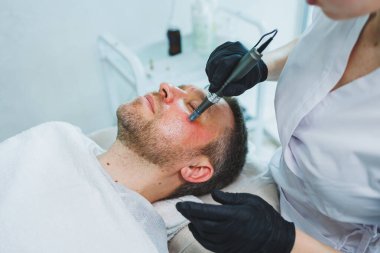 Güzellik salonunda erkek kozmetolojisi. Bir erkek yüz derisine dikkat eder..
