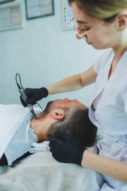 Bir kozmetikçi bir adamın derisini temizler. Kozmetik kliniğinde yüz ameliyatı yapan bir adam. Erkek kozmetolojisi.