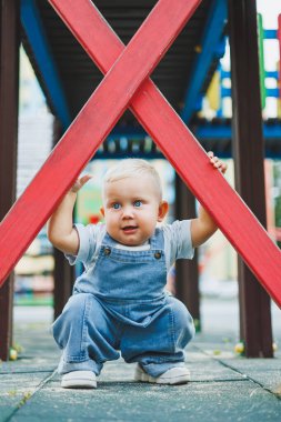 Kot pantolon giymiş küçük bir çocuk oyun parkında koşup oynuyor. Çocuğun dışarıdaki aktif zamanı. Yazın sokakta koşan bir çocuk..