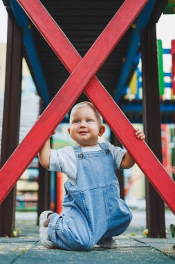 Kot pantolon giymiş küçük bir çocuk oyun parkında koşup oynuyor. Çocuğun dışarıdaki aktif zamanı. Yazın sokakta koşan bir çocuk..