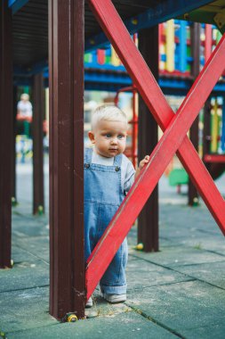 Kot pantolon giymiş küçük bir çocuk oyun parkında koşup oynuyor. Çocuğun dışarıdaki aktif zamanı. Yazın sokakta koşan bir çocuk..