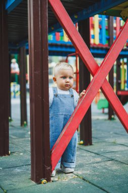 Kot pantolon giymiş küçük bir çocuk oyun parkında koşup oynuyor. Çocuğun dışarıdaki aktif zamanı. Yazın sokakta koşan bir çocuk..