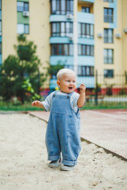 Kot pantolon giymiş küçük bir çocuk oyun parkında koşup oynuyor. Çocuğun dışarıdaki aktif zamanı. Yazın sokakta koşan bir çocuk..