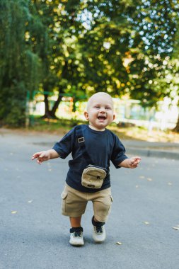 Sarışın bir çocuk sokakta yürür ve oynar. Sokakta yürüyen bir çocuk.