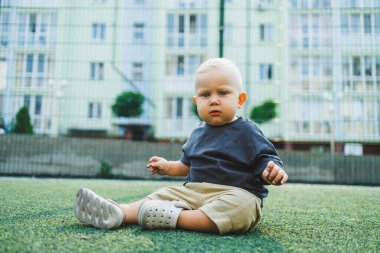 Yeşil çimlerin üzerinde yatan tatlı çocuk. Çocuğun dışarıdaki aktif zamanı. Yazın sokakta koşan bir çocuk..