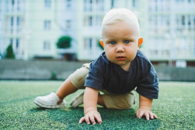 Yeşil çimlerin üzerinde yatan tatlı çocuk. Çocuğun dışarıdaki aktif zamanı. Yazın sokakta koşan bir çocuk..