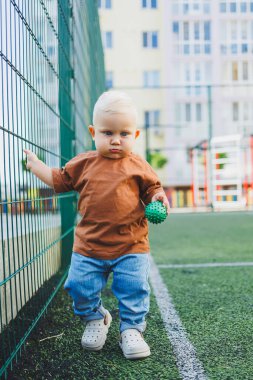 Futbol sahasında koşan tatlı çocuk. Çocuğun dışarıdaki aktif zamanı. Yazın sokakta bir çocuk koşar. Kotlu ve tişörtlü bir çocuk. Şık bir çocuk.