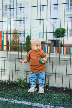 Futbol sahasında koşan tatlı çocuk. Çocuğun dışarıdaki aktif zamanı. Yazın sokakta bir çocuk koşar. Kotlu ve tişörtlü bir çocuk. Şık bir çocuk.