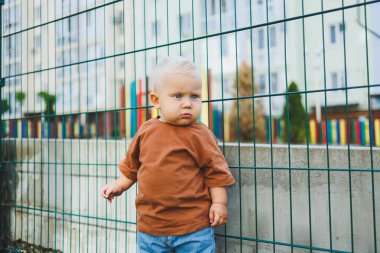 Futbol sahasında koşan tatlı çocuk. Çocuğun dışarıdaki aktif zamanı. Yazın sokakta bir çocuk koşar. Kotlu ve tişörtlü bir çocuk. Şık bir çocuk.