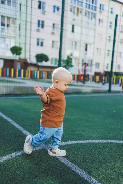 Futbol sahasında koşan tatlı çocuk. Çocuğun dışarıdaki aktif zamanı. Yazın sokakta bir çocuk koşar. Kotlu ve tişörtlü bir çocuk. Şık bir çocuk.