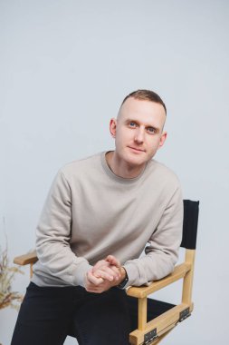 Genç bir adam sandalyeye oturur ve duygularını kameraya gösterir..