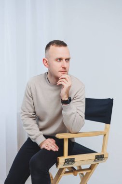 Genç bir adam sandalyeye oturur ve duygularını kameraya gösterir..