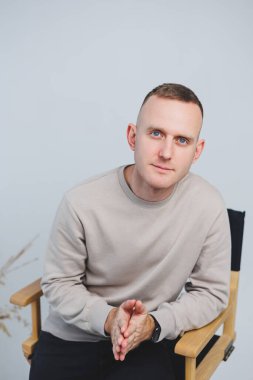 Genç bir adam sandalyeye oturur ve duygularını kameraya gösterir..