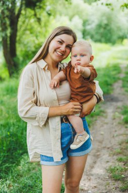 Genç bir anne küçük oğlunu kollarına alır ve parkta yürür. Oğluyla bir annenin yürüyüşü..
