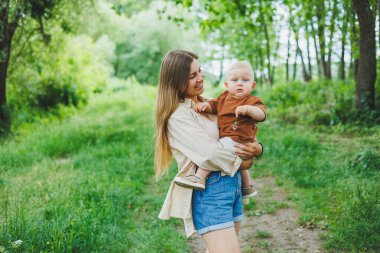 Genç bir anne küçük oğlunu kollarına alır ve parkta yürür. Oğluyla bir annenin yürüyüşü..