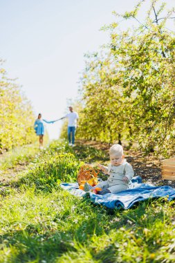 Bebek dışarıda yeşil çimlerin üzerinde oturuyor. Ailesinin geçmişine karşı bir çocuk..