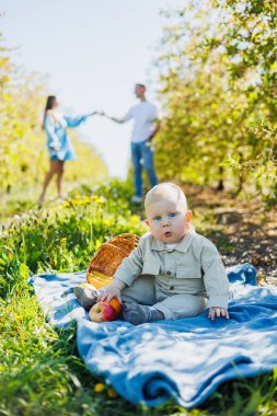Bebek dışarıda yeşil çimlerin üzerinde oturuyor. Ailesinin geçmişine karşı bir çocuk..