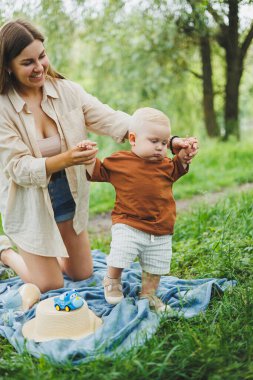 Annesinin küçük oğluyla geçirdiği zaman. Genç bir anne parktaki çimlerin üzerinde oturuyor. Oğluyla bir annenin yürüyüşü..