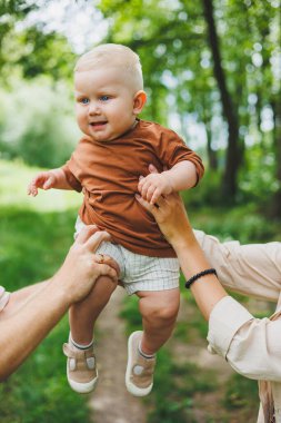 Küçük oğlan, anne ve babanın ellerinde yakın plan. Ebeveynler oğullarını ellerinde tutarlar..